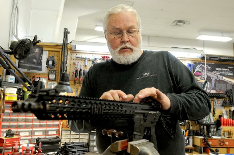 Jim Watson of Huntsville attaches a rear sight to an AR-15 semiautomatic rifle Wednesday at Wilson Combat, a maker of firearms in Berryville that is restricting sales to some law-enforcement agencies. 