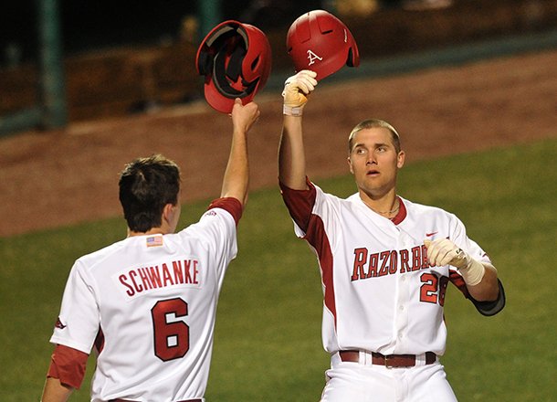 Arkansas batter Isaac Hellbusch is greeted at home plate by teammate Willie Schwanke after hitting a two-run home run in the fourth inning in Tuesday night's game against Alabama A&M at Baum Stadium in Fayetteville.