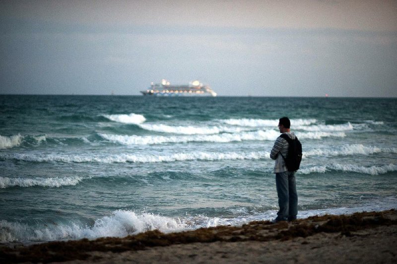 A cruise ship sits in the ocean as a man stands near the water on the shore in Miami Beach, Florida, U.S., on Wednesday, Feb. 20, 2013. U.S. exports in the travel and tourism sector reached $168.1 billion in 2012, up 10.1 percent from the year-ago level of $152.7 billion, according to data released Feb. 22 by the Commerce Department's International Trade Administration. Photographer: Ty Wright/Bloomberg