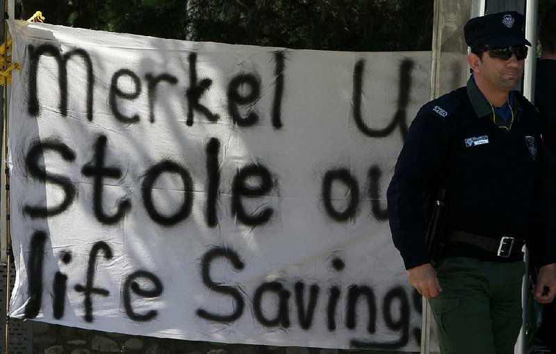 A police officer stands near a protest banner Monday outside the parliament building before a meeting in Nicosia, Cyprus. 