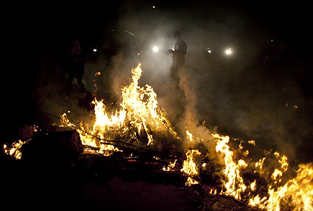 An Egyptian activist walks by burning tires during an anti-Muslim Brotherhood protest in front of the Brotherhood’s headquarters Sunday in Cairo. 