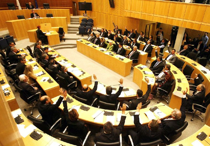 Members of parliament vote against a crucial plan to seize a part of depositors' bank savings, in Nicosia, Tuesday, March 19, 2013. Cypriot lawmakers on Tuesday rejected a critical draft bill that would have seized part of people's bank deposits in order to qualify for a vital international bailout, with not a single vote in favor. (AP Photo/Philippos Christou)