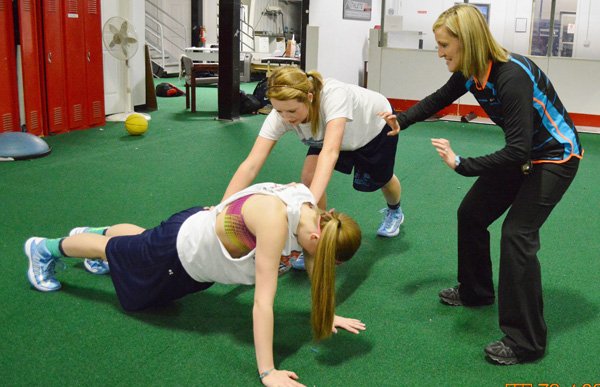Paige White, Springdale Har-Ber trainer, right, works with Har-Ber athletes during a training session. White was selected as one of 14 elite trainers by Alan Stein, who conducts clinics across the country. 