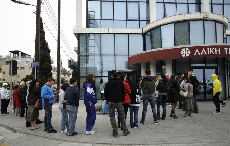 Cypriots wait to use an ATM outside a closed Laiki bank branch in the southern port city of Limassol on Thursday. The bank on Thursday capped daily withdrawals at $340 per person, down from $906. 