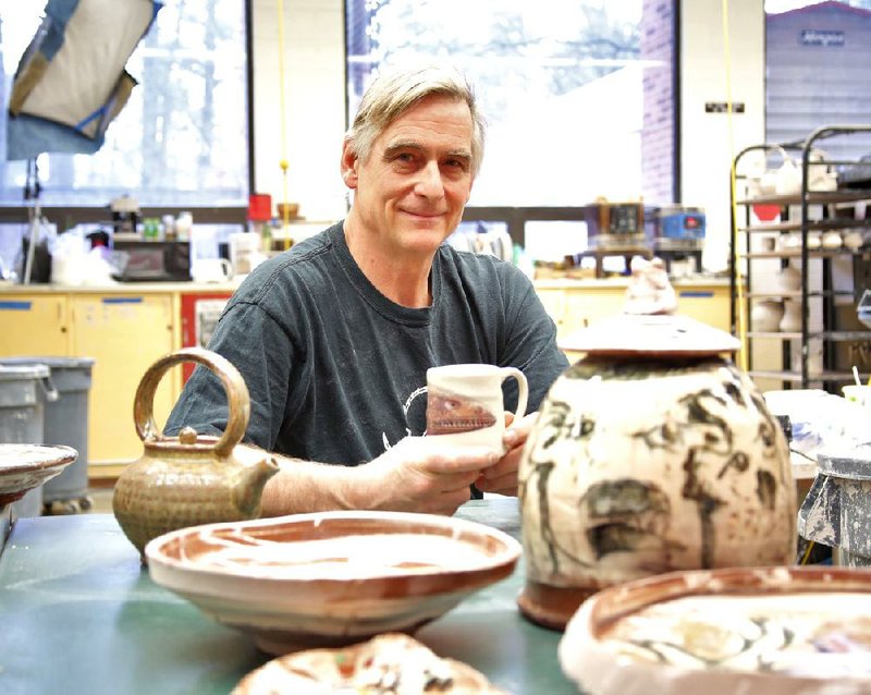 Potter Stephen Driver sits with pots by acclaimed potter Ron Meyers (foreground) and his own, the mug he holds and a teapot at left. Driver, assistant professor of art at the University of Arkansas at Little Rock, has co-curated a show for Meyers, his teacher, at the Arkansas Arts Center. 