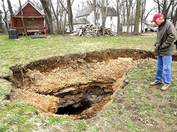 
Preston Barrett stands beside a large sinkhole which opened up in the backyard of his home in Springtown earlier this month. His wife Karee discovered the new feature in their yard when going to check some fruit trees in the early morning hours of March 2. She said she came close to stepping into the hole before she realized it was there.