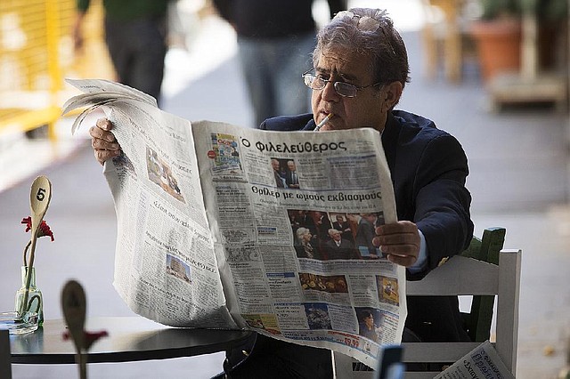 A man catches up on the news at a cafe in Nicosia, Cyprus, on Monday. Cypriot President Nicos Anastasiades agreed early Monday morning to shut Cyprus Popular Bank and tax deposits of more than $130,000 in Cypriot banks in a plan to secure emergency funds from the European Central Bank and the International Monetary Fund. 