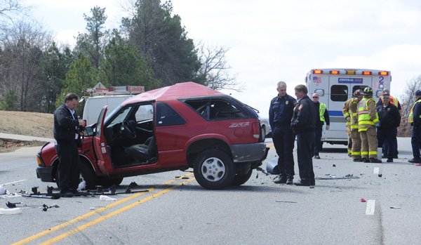 Fayetteville emergency personnel collect information Tuesday and clean up after a three-vehicle collision involving a Chevrolet Blazer, a Fayetteville Fire Department ladder truck and a city water and sewer truck on South Crossover Road south of Lovers Lane in Fayetteville. 