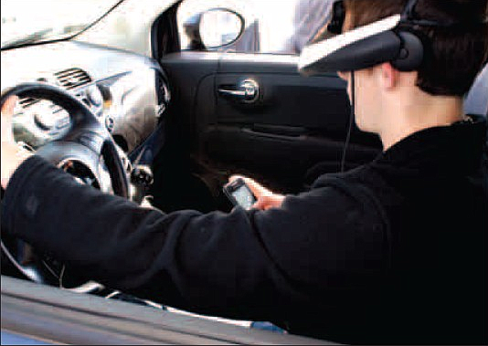 Derek Pruitt uses his cell phone in the driving-while-texting simulator which was at Gravette High School before spring break. 