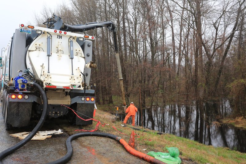 Workers continue to siphon crude oil from a creek along a frontage road on the east side of Interstate 40 in Mayflower Saturday after a pipeline rupture Friday in the Northwood subdivision in Mayflower.
