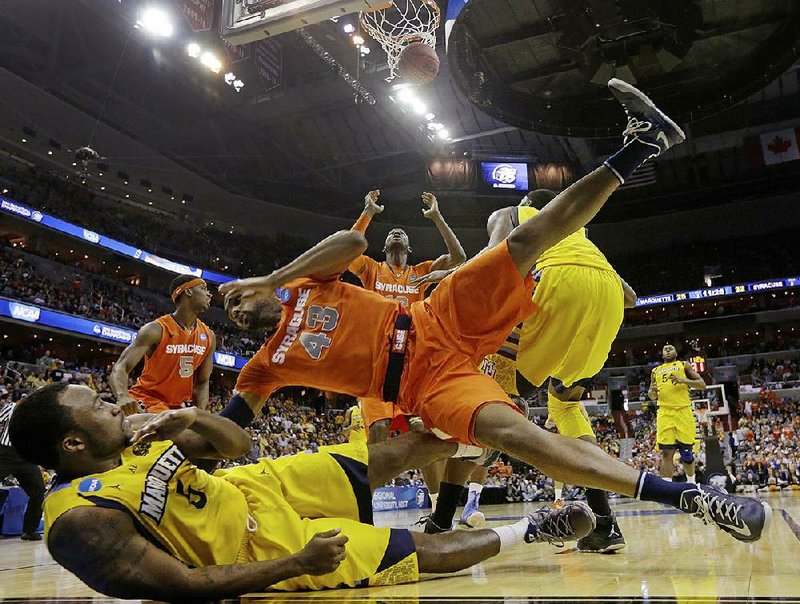 Syracuse forward James Southerland (43) lands on Marquette guard Junior Cadougan (5) as Syracuse center Baye Keita (12) looks for the rebound during the second half of the East Regional final in the NCAA men's college basketball tournament, Saturday, March 30, 2013, in Washington. (AP Photo/Pablo Martinez Monsivais)