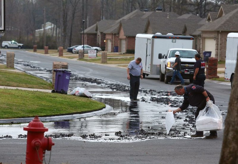 Firefighters drop absorbent cloths on the ground where oil flowed down North Starlite Road in Mayflower’s Northwood subdivision, after crews stopped the flow of oil from a pipeline break Friday, March 29, 2013. 