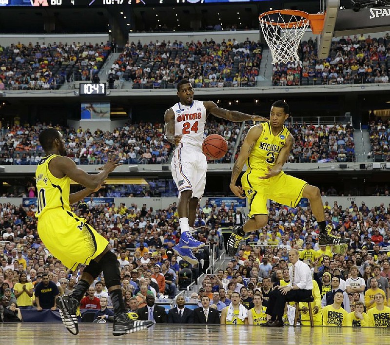 Michigan guard Trey Burke (3) makes a pass to Tim Hardaway Jr. (10) as Casey Prather (24) defends during the second half of Sunday’s South Regional final in Arlington, Texas. Burke had seven assists and 15 points and Hardaway finished with nine points as Michigan won 79-59. 