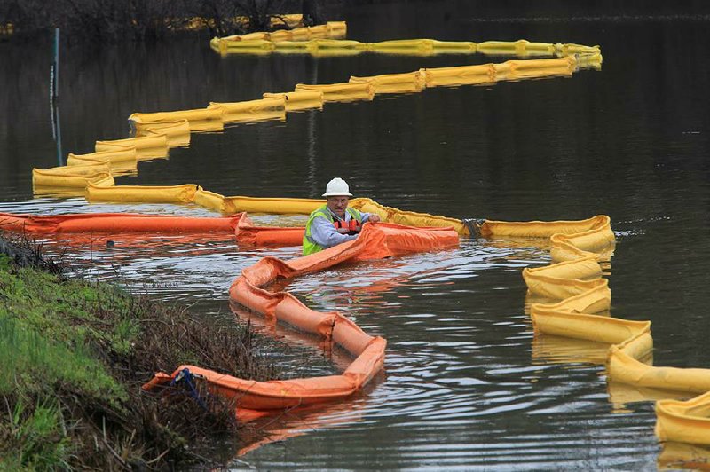 A worker puts out an oil-spill containment boom in Lake Conway near Arkansas 89 in Mayflower on Sunday morning as workers continue to clean up after Friday's oil spill in the Northwood subdivision in Mayflower. 