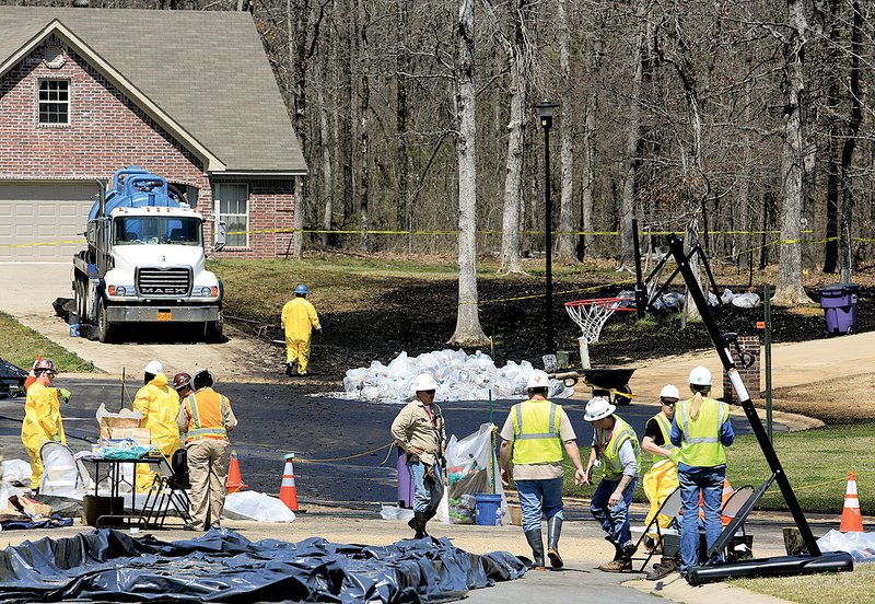 Workers in protective gear clean crude oil off the street Monday at Shadetree Lane and North Starlite Road in Mayflower. Photos from the Mayflower oil spill are available at arkansasonline.com/galleries. 