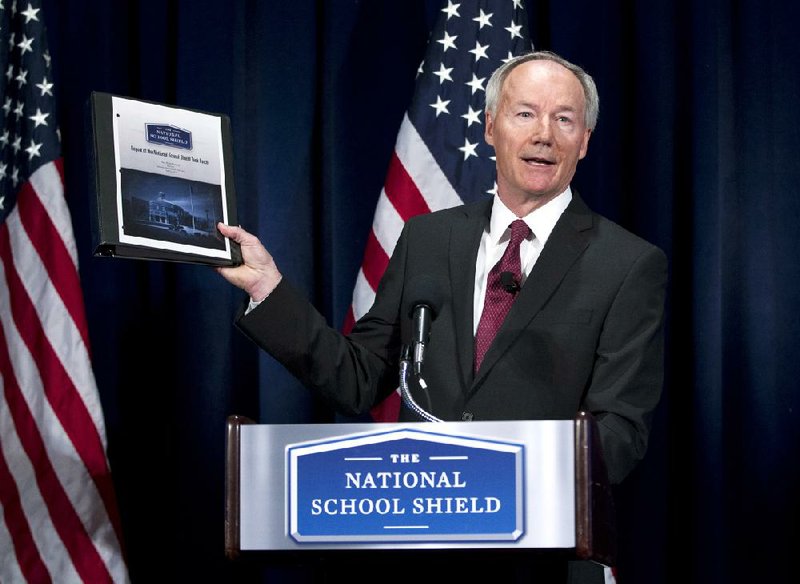 National School Shield Task Force Director, former Arkansas Rep. Asa Hutchinson, holds a copy of group's study during a news conference at National Press Club in Washington, Tuesday, April 2, 2013. The National Rifle Association's study recommends schools across the nation each train and arm at least one staff member.  (AP Photo/Jose Luis Magana)