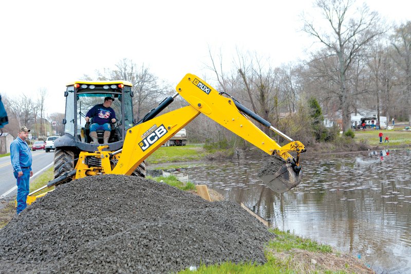 Mayflower Street Superintendent Jimmy Johnson, left, oversees Mayflower Water Department employee Brad Lawrence as he works Friday on a retention pond on Highway 89 in Mayflower, following a nearby crude-oil spill. Culverts were plugged to keep oil from entering Lake Conway, and dikes were built Friday shortly after authorities were alerted to an Exxon Mobil underground pipeline that ruptured at Shade Tree Lane and North Starlite Road in the Northwoods subdivision, less than a mile from Lake Conway. Faulkner County Judge Allen Dodson said workers are vacuuming water and oil from ditches and yards and placing the mixture into “frac tanks.”