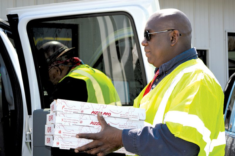 An employee of United States Environmental carries some of the 20 pizzas the company ordered Monday from Yogo City in a Mayflower shopping center. The company also bought 30 footlong sandwiches from Subway. Oil-spill cleanup crews have been frequenting restaurants in the center, boosting business, managers said.