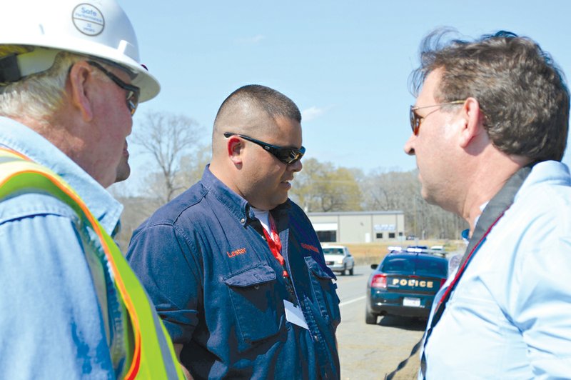 Scott Smith, right, talks with two Exxon Mobil officials who said they were not allowed to give their names to the media. Smith, of Cape Cod, Mass., was questioned about putting a foam product in the oily stormwater ditch on U.S. 365 in Mayflower. Smith said he used his product in another oil spill with Exxon Mobil’s blessing, but company officials said they did not give him permission to do so in Mayflower. 
