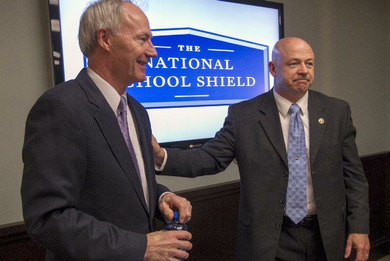 Former U.S. Rep. Asa Hutchinson (left), director of the National School Shield initiative, talks with Boone County Sheriff Mike Moore on Wednesday about recommendations in a report by the initiative financed by the National Rifle Association. 