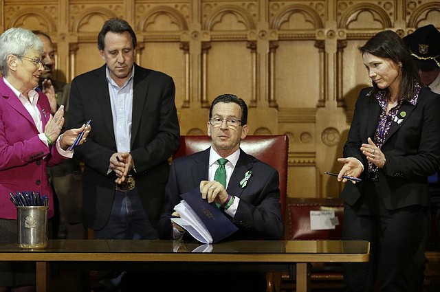 Connecticut Gov. Dannel Malloy (center) completes signing legislation Thursday in Hartford that includes new restrictions on weapons and large-capacity ammunition magazines. 