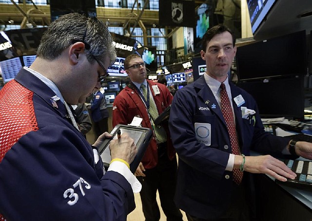 Specialist John McNierney (right) works Thursday at his post on the floor of the New York Stock Exchange. 