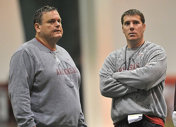 Arkansas assistant coaches Sam Pittman (left) and Chris Ash work with the Razorbacks during practice Saturday morning in Fayetteville.