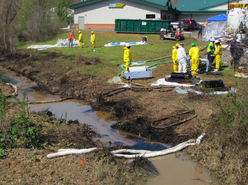 Workers clean up oil in a drainage area in Mayflower Friday.