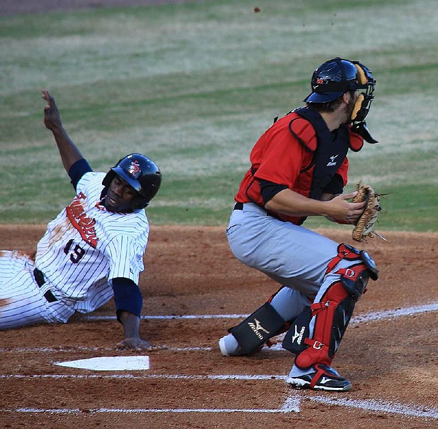 Arkansas Travelers centerfielder Travis Witherspoon (left) slides safely into home behind Frisco’s Zach Zaneski during the first game of Friday’s doubleheader at Dickey-Stephens Park in North Little Rock. 