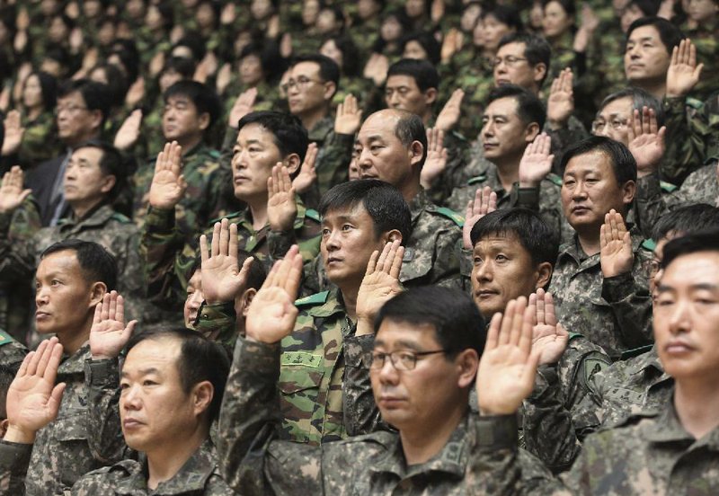 South Korean army reservists show their support for a resolution against North Korea during a gathering Friday at a gymnasium in Seoul. The military tension between the two Koreas has begun to strain the South’s economy. 