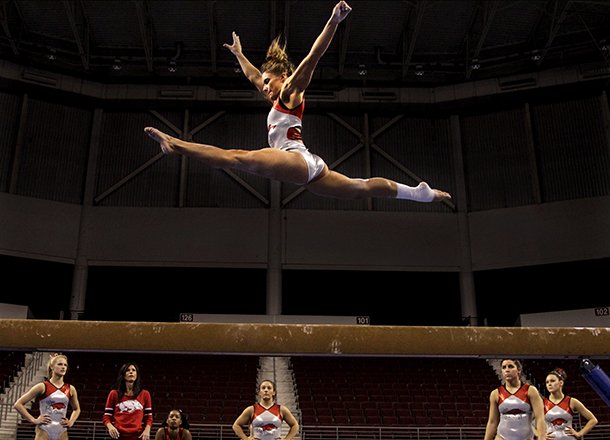 Arkansas gymnastics coach Rane Lyst, second from left, watches Katherine Grable on the balance beam with other members of the team during a practice session Friday at Verizon Arena in North Little Rock in preparation for Saturday's SEC Gymnastics championships.