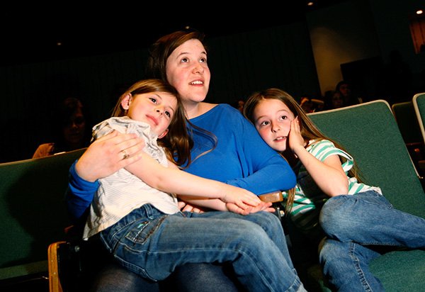 Rhiannon (cq) Steele and her daughters, Eve Steele (left), 5, and Carolyn Steele, 8, all of Farmington watch the screen as it displays student names for the Northwest Arkansas Classical Academy on Friday, April 5, 2013, at NorthWest Arkansas Community College in Bentonville. The new charter school coming to Bentonville held a lottery to determine which students it will accept from the applications it has received.