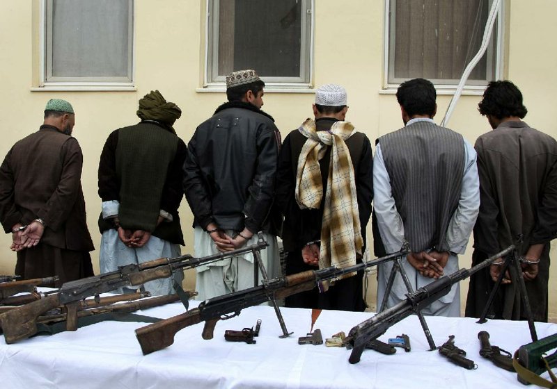 Former Taliban militants stand in line handcuffed after turning in their weapons during a peace-reconciliation ceremony with the Afghan government in Herat, Afghanistan, on Sunday. 