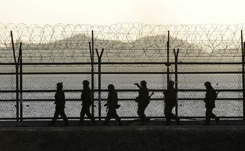 South Korean soldiers patrol along a barbed-wire fence at sunset near the border village of Panmunjom, which has separated the two Koreas since the Korean War, in Paju, north of Seoul, South Korea, on Sunday. 