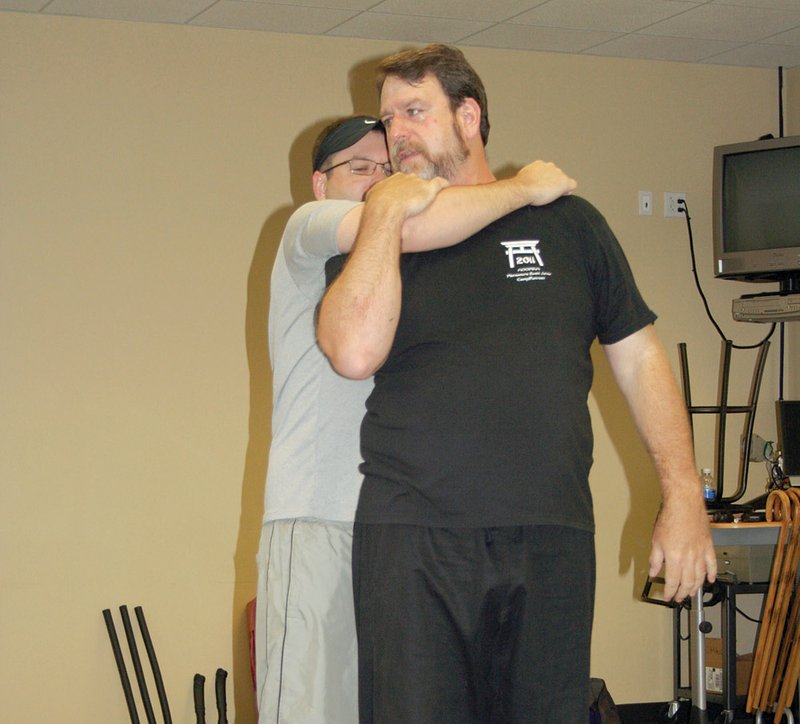 Instructor Don Gregory shows how to release yourself from a choke hold while student Josh Kemp pretends to attack during a self-defense class at the University of Arkansas Community College at Batesville.