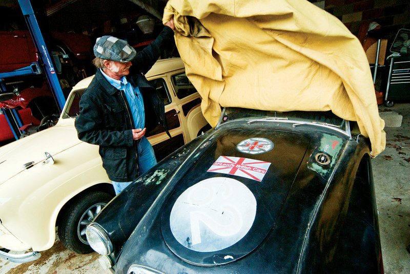 Ronnie McLeod pulls the cover off an MGA he has at his shop, McLeod British Cars, in Maumelle.