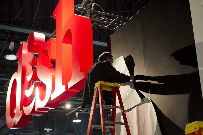 A worker installs a display at the Dish Network booth during the 2013 Consumer Electronics Show in Las Vegas, Nevada, U.S., on Tuesday, Jan. 8, 2013. The 2013 CES trade show, which runs until Jan. 11, is the world's largest annual innovation event that offers an array of entrepreneur focused exhibits, events and conference sessions for technology entrepreneurs. Photographer: Andrew Harrer/Bloomberg