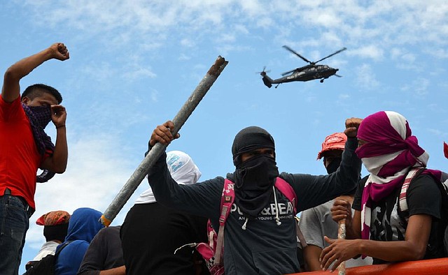 Young teachers block a major highway last week, one holding a metal pipe, as a federal police helicopter flies overhead in Chilpancingo, Mexico. 