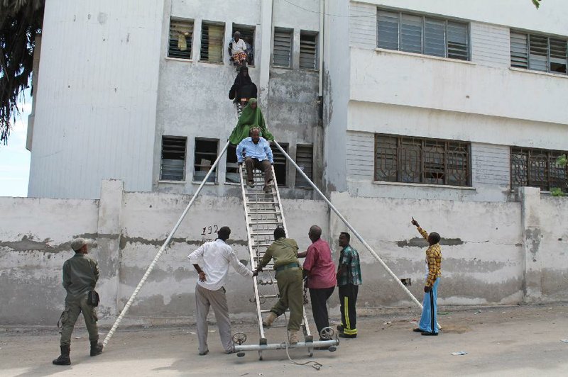 People are helped to escape from a window during an attack at Mogadishu’s court complex Sunday in Mogadishu, Somalia. 