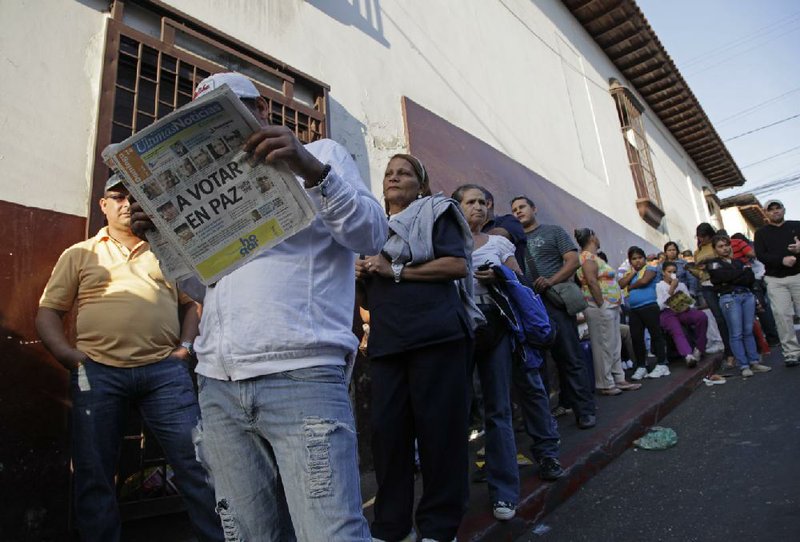 Residents wait in line at a polling station during the presidential election in Caracas, Venezuela, on Sunday. The newspaper’s headline reads in Spanish, “Vote in Peace.” 