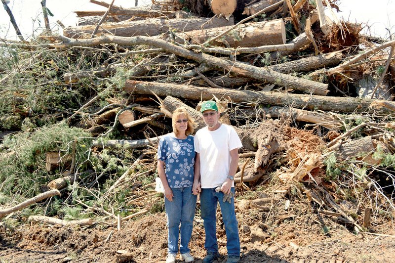 Jamois and Roger Sweatt of the Walnut Grove community in Van Buren County stand in front of a tower of trees that volunteers cleared from the Sweatts’ property after an April 10 tornado. The back of their home received some damage, and outbuildings were destroyed. About a half-dozen homes on Hardy Hill Road, including theirs, were hit by the EF2-rated tornado.