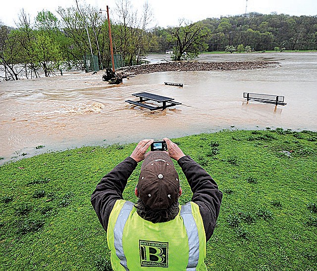 Robert Brown of the Bentonville Parks and Recreation Department snaps a photo Thursday of floodwaters overrunning the dam at Lake Bella Vista Park.