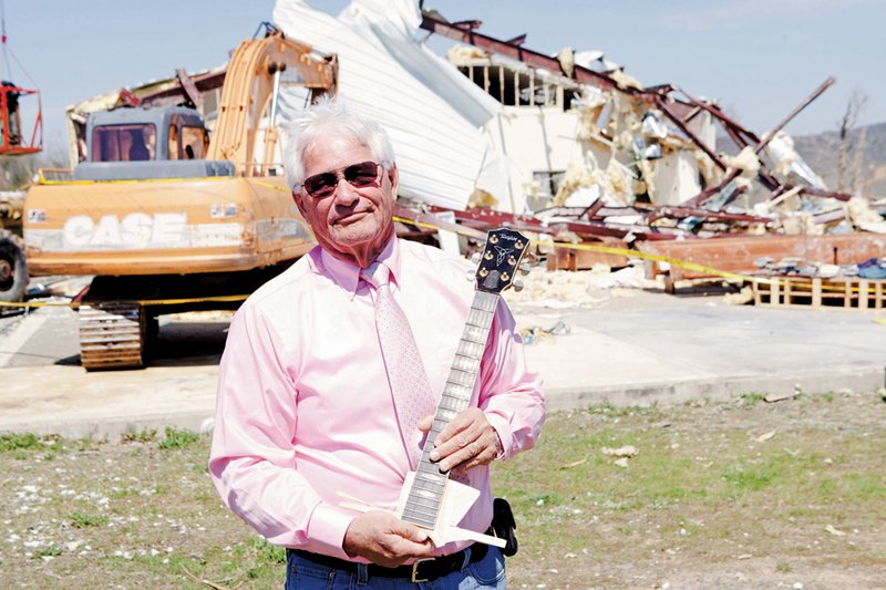 Ester Bass of Shirley, pastor of the Botkinburg Foursquare Church in Van Buren County, holds the neck of his beloved Taylor guitar, the only part that survived an April 10 tornado. “I loved that guitar,” he said.