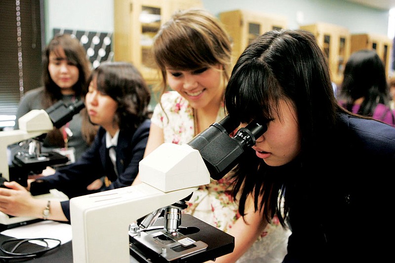 Mana Matsuyama, right, from Tennoji High School, shares a microscope with Megan Graham of the Arkansas School for Mathematics, Sciences and the Arts in Hot Springs in 2012, when students from the school in Osaka, Japan, visited Hot Springs. Students from Osaka will make another visit to ASMSA on Monday, while 22 students from the Hot Springs school prepare for a trip to Japan at the end of the month.
