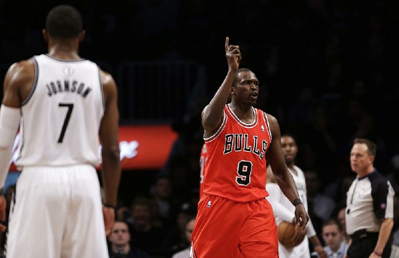 Chicago Bulls forward Luol Deng (9) celebrates near the end of the second half of Game 2 of their first-round NBA basketball playoff series as Brooklyn Nets guard Joe Johnson (7) walks away, Monday, April 22, 2013, in New York. The Bulls won 90-82. (AP Photo/Kathy Willens)