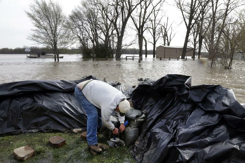 Bob Bailey tinkers with a pump as he tries to keep floodwaters from the Mississippi River out of one of his rental properties Sunday in Clarksville, Mo. 