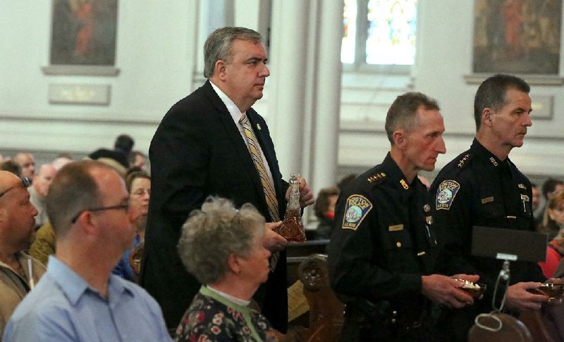 Boston Police Commissioner Ed Davis (left) and Superintendents William Evans and Kevin Buckley carry the “Gifts” to the altar during Mass at the Cathedral of the Holy Cross on Sunday in Boston. Prayers were said for the victims of the Boston Marathon bombings and the subsequent manhunt and for fi rst responders. 