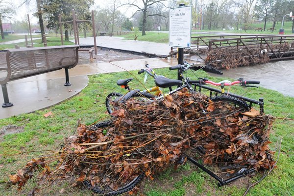 Debris clings to bicycles and a pedestrian bridge on Thursday April 18 2013 along the Rogers trail system. Little Osage Creek flooded early Thursday and caused some roads to be closed on the city's west side.