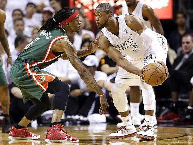 Miami Heat guard Dwyane Wade (3) looks for an open teammate past Milwaukee Bucks forward Marquis Daniels during the second half of Game 2 in their first-round NBA basketball playoff series, Tuesday, April 23, 2013 in Miami. The Heat defeated the Bucks 98-86. (AP Photo/Wilfredo Lee)