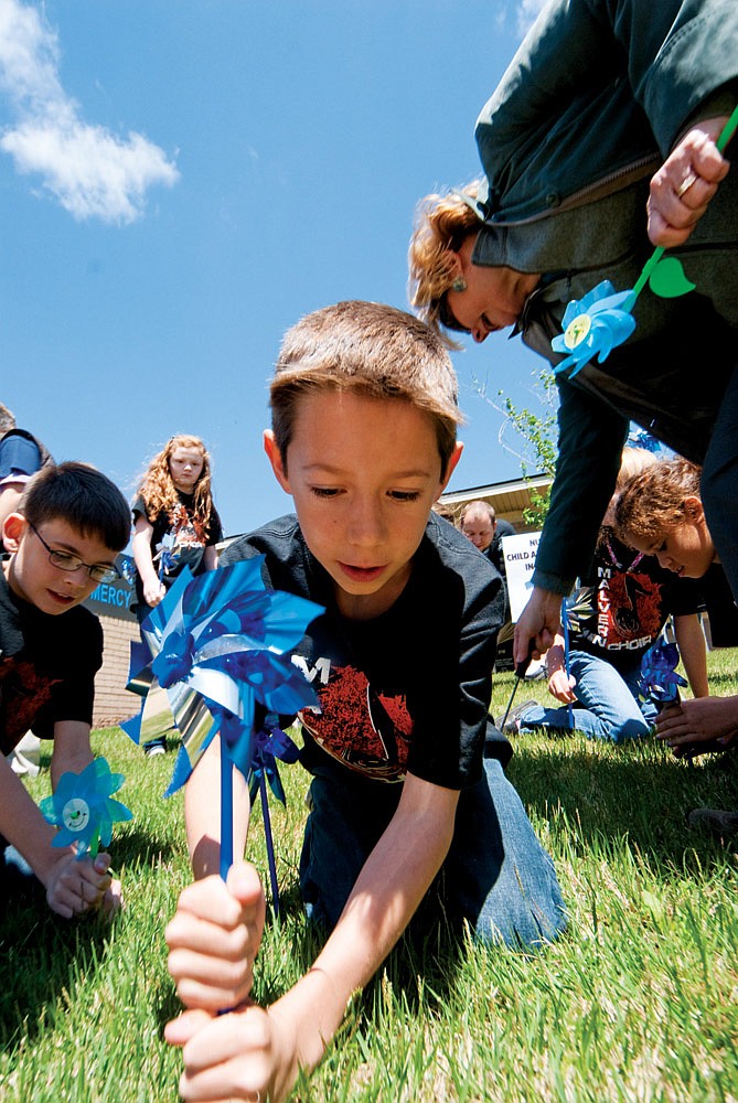 Hayden Woods, a fourth-grader at Malvern Elementary School, places a pinwheel at the recent Child Abuse Awareness Rally at the Cooper-Anthony Mercy Child Advocacy Center in Hot Springs.